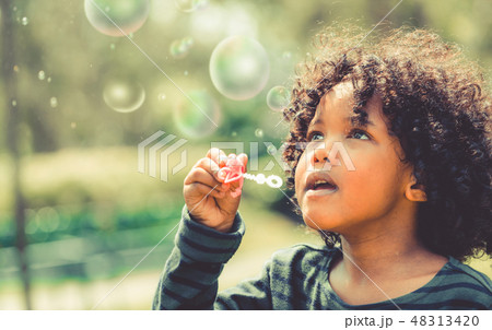 Happy little kid blowing bubble in school garden. Happy little kid blowing bubble in school garden. 48313420
