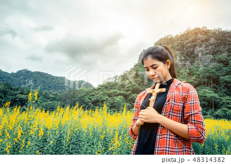 Young beautiful woman praying on nature background Young beautiful woman praying on nature background 48314382
