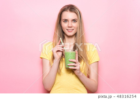 Cute young woman drinking a green smoothie 48316254