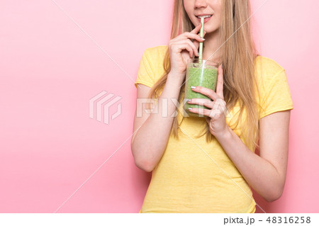 Cute young woman drinking a green smoothie Cute young woman drinking a green smoothie 48316258