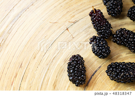 The mulberry fruit in white bowl on wood table. 48318347