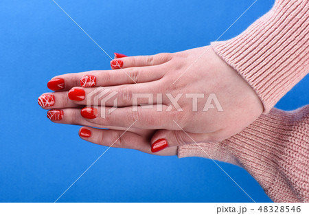 Hands of a girl in beige sweater with red manicure Hands of a girl in beige sweater with red manicure 48328546