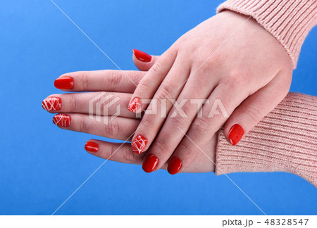 Hands of a girl in beige sweater with red manicure Hands of a girl in beige sweater with red manicure 48328547