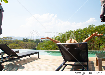 Happy woman relaxing near swimming pool 48330244