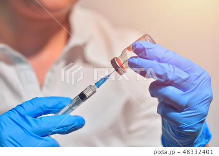 Closeup of vaccine bottle with syringe and needle 48332401