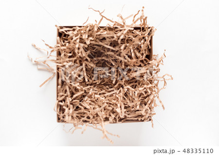 Opened gift box with decorative straws fillers on light background. Brown craft paper box for your Opened gift box with decorative straws fillers on light background. Brown craft paper box for your 48335110