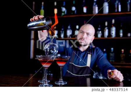 Fiery show at the bar. The bartender makes hot alcoholic cocktail and ignites bar. Bartender 48337514