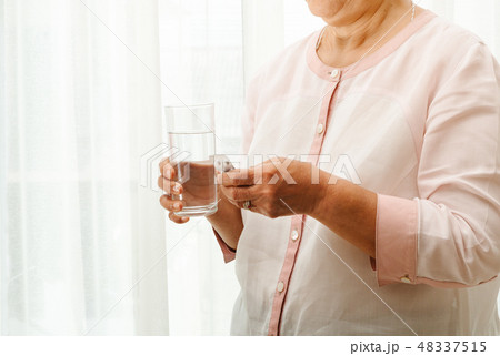 senior women take medicine with a glass of water 48337515