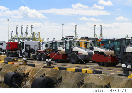 Asphalt roller and trucks waiting loading on a shi 48339739