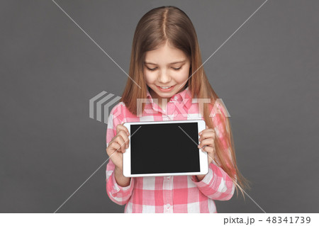 Freestyle. Girl standing isolated on grey looking at screen of digital tablet excited close-up Freestyle. Girl standing isolated on grey looking at screen of digital tablet excited close-up 48341739