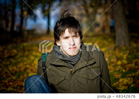 Young man sitting in autumn park 48342676