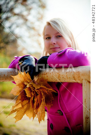 Young blonde woman in violet coat in park 48342721