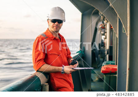 Deck Officer on deck of offshore vessel holds VHF walkie-talkie radio Deck Officer on deck of offshore vessel holds VHF walkie-talkie radio 48342885