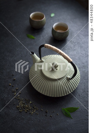 Teapot and teacups on black table Teapot and teacups on black table 48344800