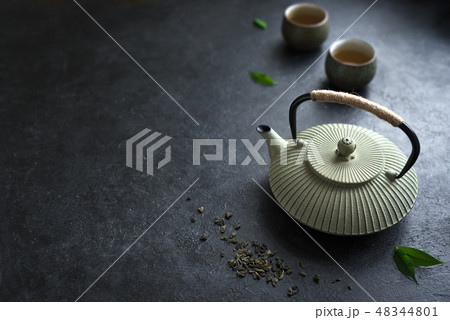 Teapot and teacups on black table Teapot and teacups on black table 48344801