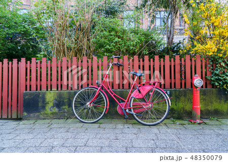 Nice Red vintage bike parked near wooden fence at city street. 48350079