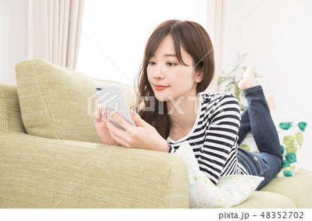 ソファーでスマホを使う女性 ソファーでスマホを使う女性 48352702