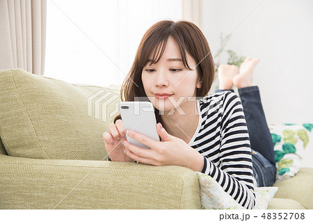 ソファーでスマホを使う女性 48352708