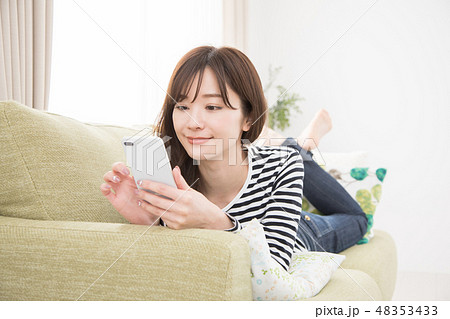ソファーでスマホを使う女性 ソファーでスマホを使う女性 48353433