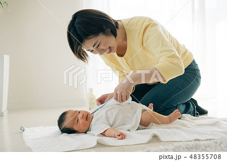 赤ちゃんに肌着を着せる若い母親 お着替え お世話 48355708