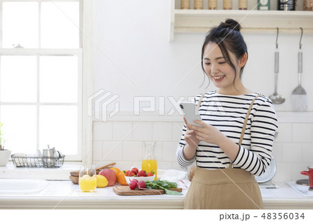 女性　スマホ　キッチン 48356034