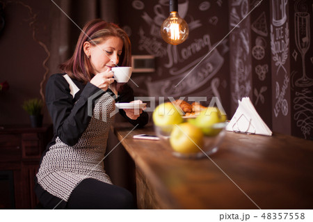 Adult woman enjoys her cup of coffe at bar counter 48357558