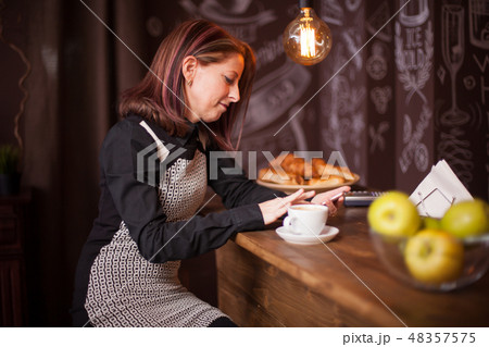 Adult businesswoman browsing on her phone at bar counter 48357575