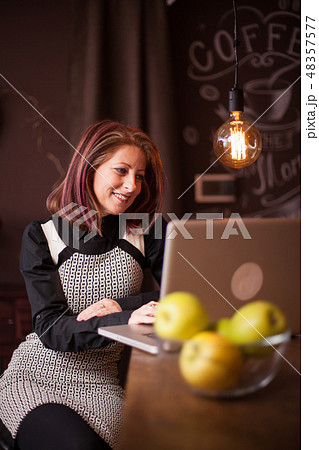 Businesswoman smiling while looking at her laptop in a vintage coffee shop 48357577