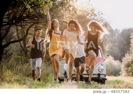 A group of young friends on a roadtrip through countryside, jumping. A group of young friends on a roadtrip through countryside, jumping. 48357582