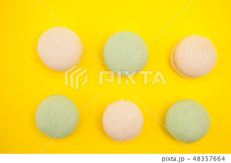 Top view of Peach and green tee macaroons in rows over yellow background Top view of Peach and green tee macaroons in rows over yellow background 48357664
