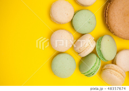 Top view of big caramel macaroon flavour next to little macaroons over yellow background Top view of big caramel macaroon flavour next to little macaroons over yellow background 48357674