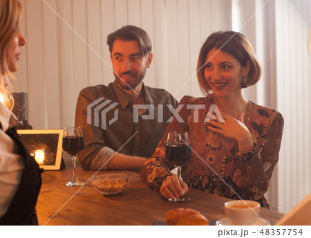 Attractive young woman enjoying a glass of red wine while talking to the bartender 48357754