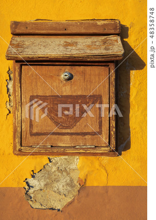 Old wooden letterbox on a yellow wall 48358748