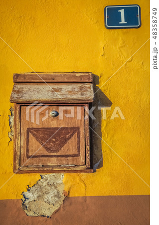 Old wooden letterbox on a yellow wall 48358749