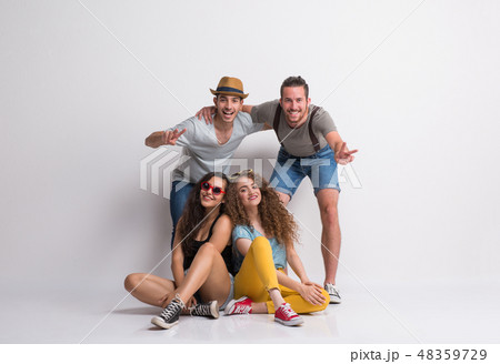 Portrait of joyful young group of friends with hat in a studio, laughing. 48359729