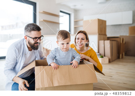 A portrait of young family with a toddler girl moving in new home. A portrait of young family with a toddler girl moving in new home. 48359812