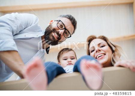 A low-angle view of young family with a toddler girl moving in new home. A low-angle view of young family with a toddler girl moving in new home. 48359815