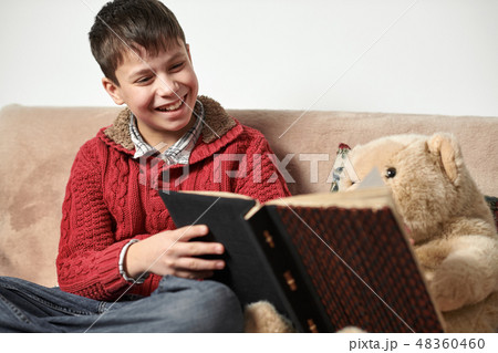 boy plays with an acoustic guitar, sits on  sofa 48360460