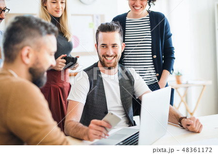 Group of young businesspeople with laptop working together in a modern office. 48361172