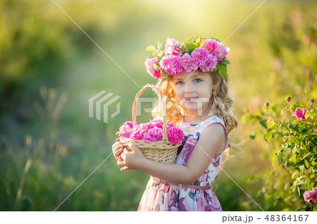 A little girl with beautiful long blond hair, dressed in a light dress and a wreath of real flowers A little girl with beautiful long blond hair, dressed in a light dress and a wreath of real flowers 48364167