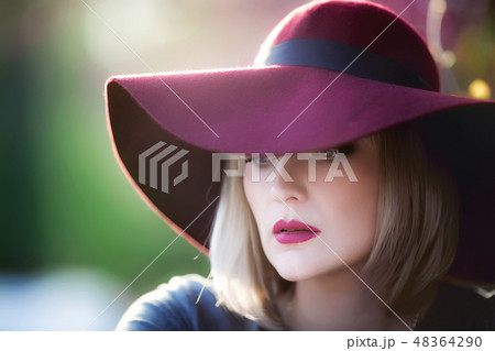 Young woman smiling on the red garden background, copy space 48364290