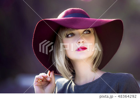 Young woman smiling on the red garden background, copy space 48364292