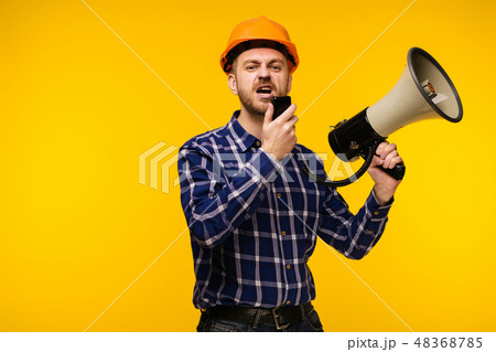 Angry worker man with a megaphone on background Angry worker man with a megaphone on background 48368785
