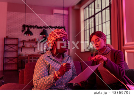 Cute long-haired young woman with long earrings discussing horoscope with the fortune-teller Cute long-haired young woman with long earrings discussing horoscope with the fortune-teller 48369705