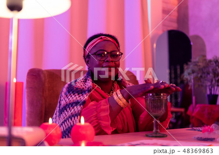 African american plump fortune-teller with a golden watch holding hands under the cup 48369863