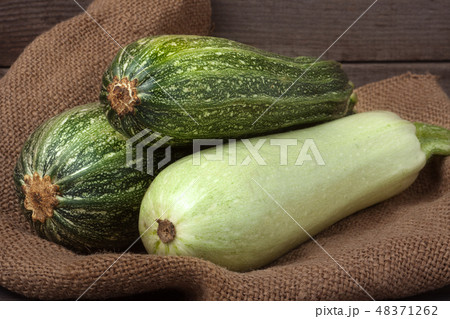 green zucchini and courgette on sackcloth wooden background 48371262