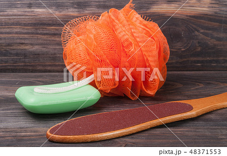 double-sided grater for feet with soap and shower sponge on a wooden background 48371553