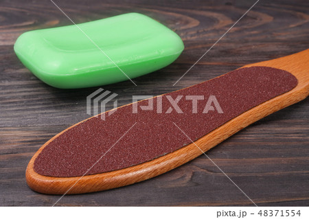 double-sided grater for feet with soap on a wooden background 48371554