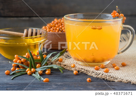 Tea of sea-buckthorn berries with a sprig on sackcloth and wooden background 48371671
