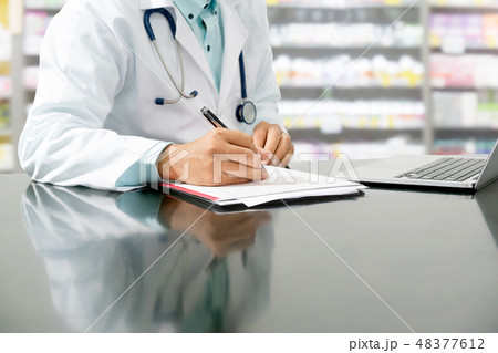 Pharmacist writes on documents at pharmacy. 48377612